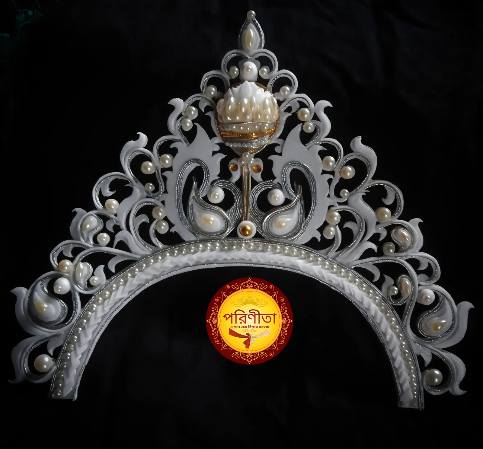 A white shola mukut, the Bengali bridal crown, hand-cut from reed pith and set with pearls, carrying the Parineeta seal